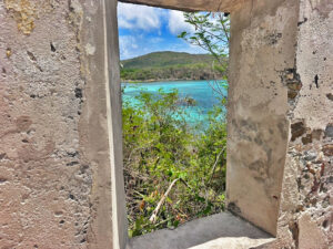 Turquoise bay and green hillside seen through a window in old stone ruins on St John, USVI