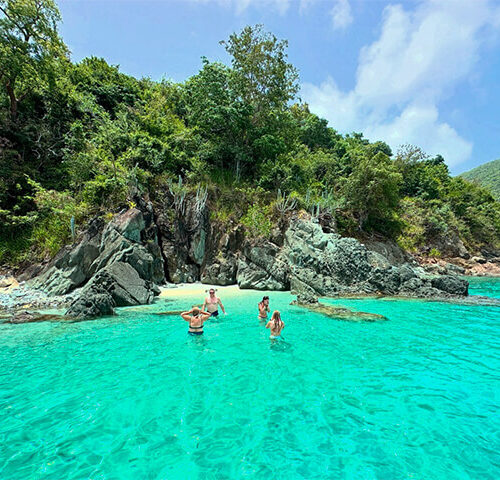 Friends swimming in a clear turquoise cove inside the Virgin Islands National Park during st john boat charters.