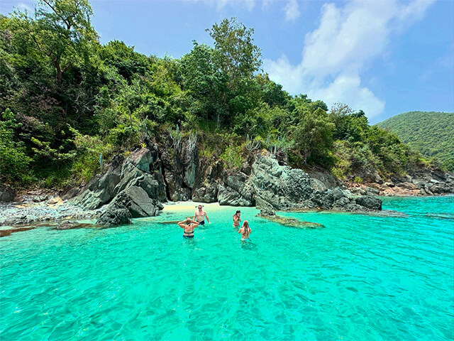 Friends swimming in a clear turquoise cove inside the Virgin Islands National Park during st john boat charters.